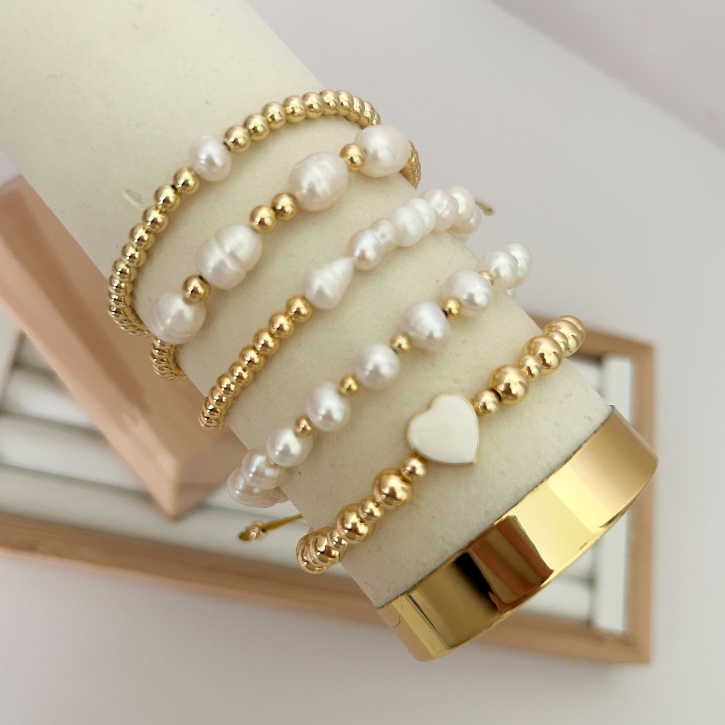 White heart pearl gold bracelet set displayed on jewelry stand