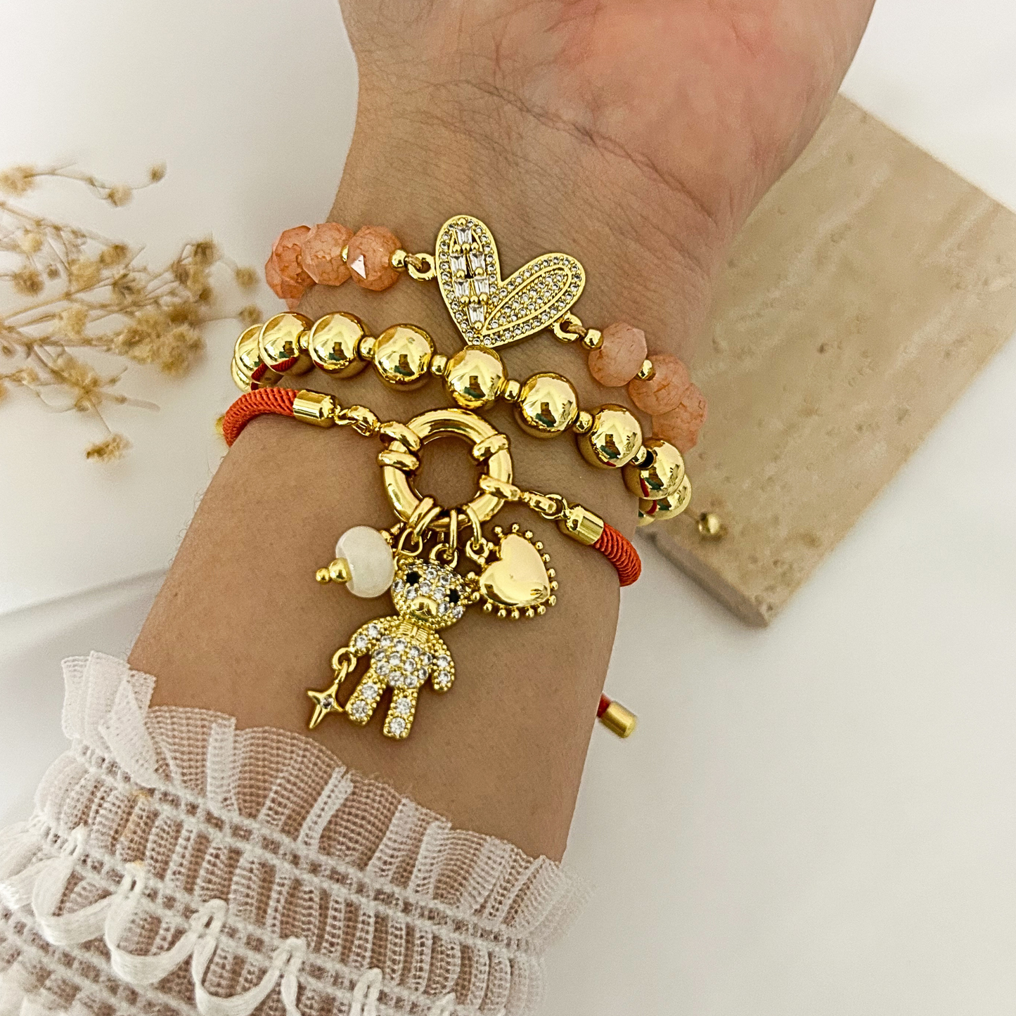Teddy bear charm bracelet stack with peach crystal and gold bead styles worn on wrist