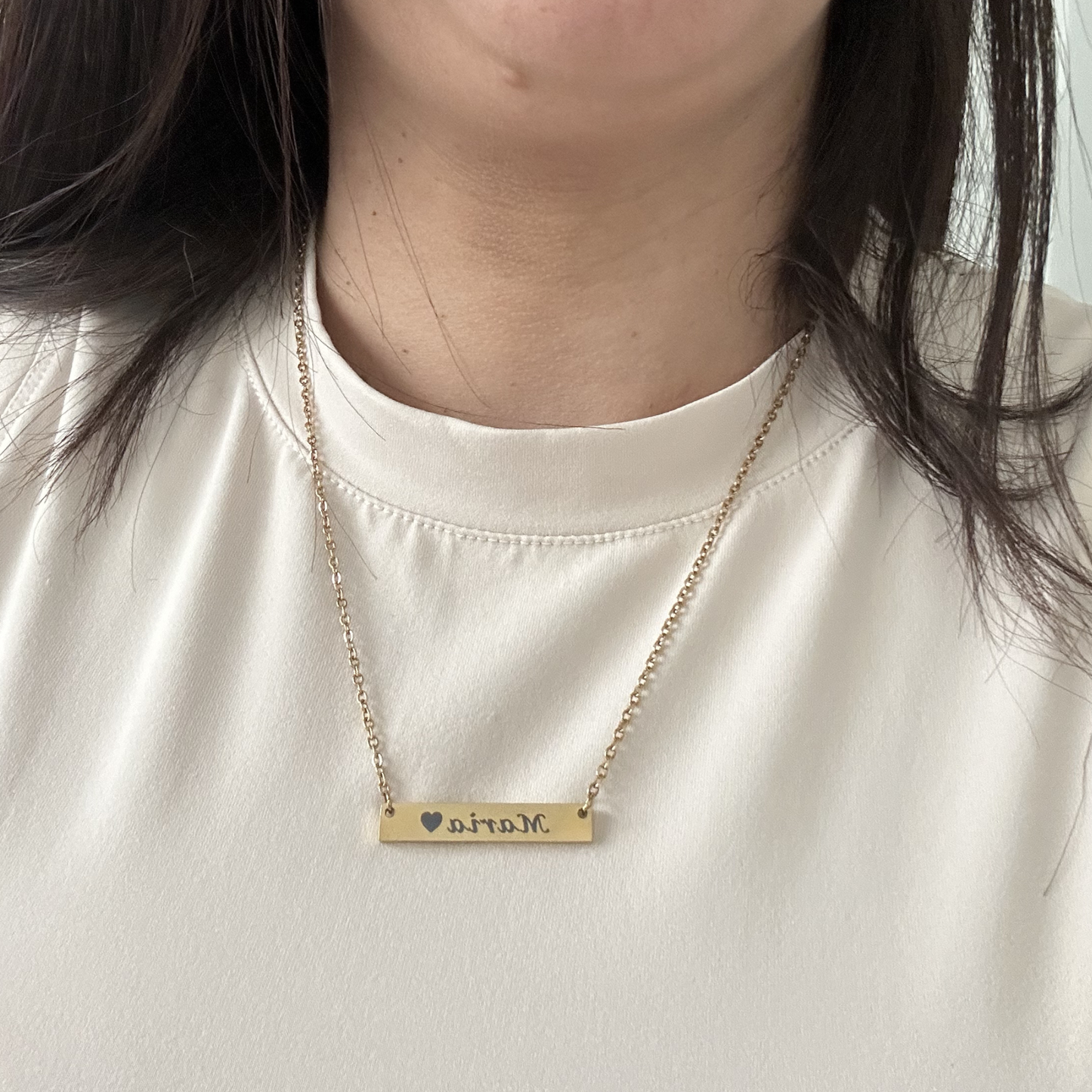 Gold necklace with 'mom' pendant on a white shirt