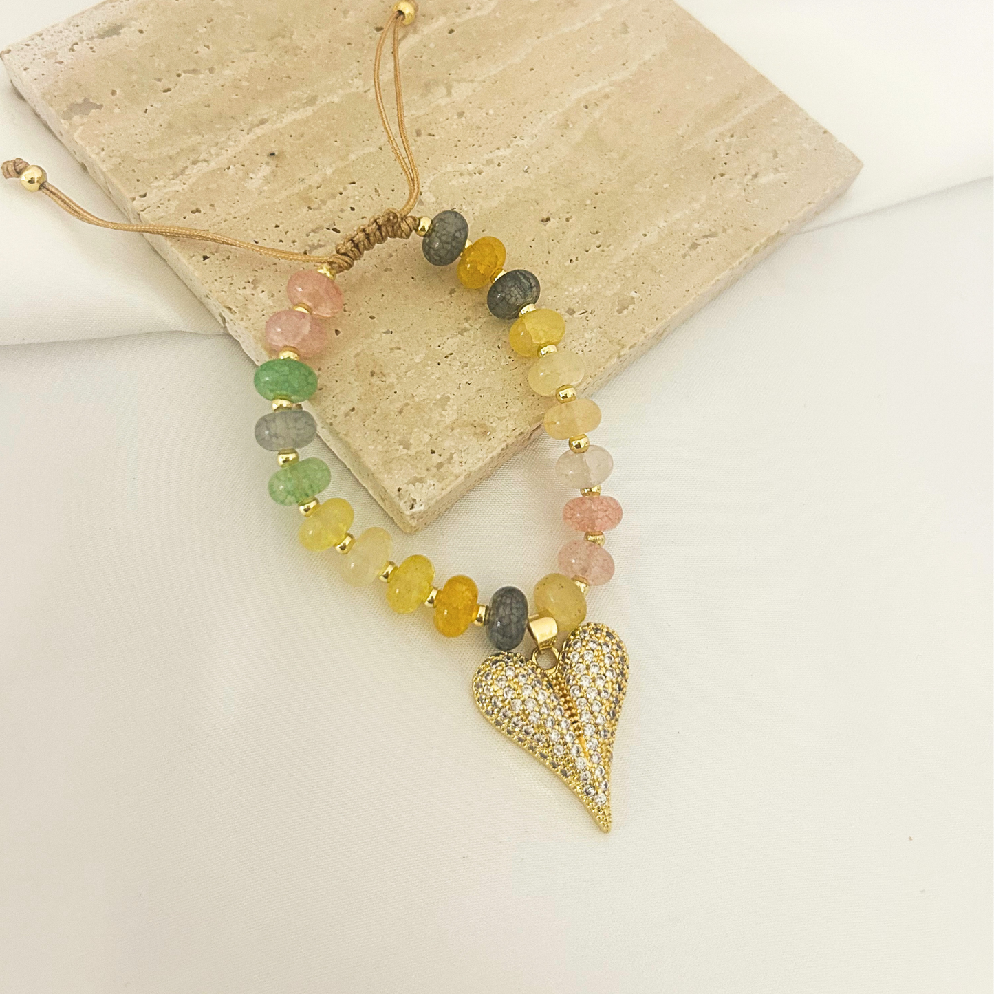 Multicolor beaded bracelet with heart pendant held in hand