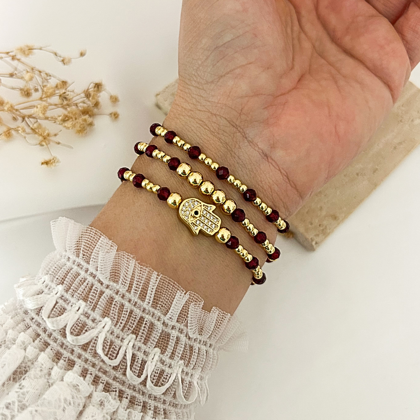 Hamsa protection bracelet stack with garnet-color crystal beads worn on wrist