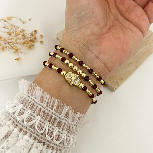Hamsa protection bracelet stack with garnet-color crystal beads worn on wrist
