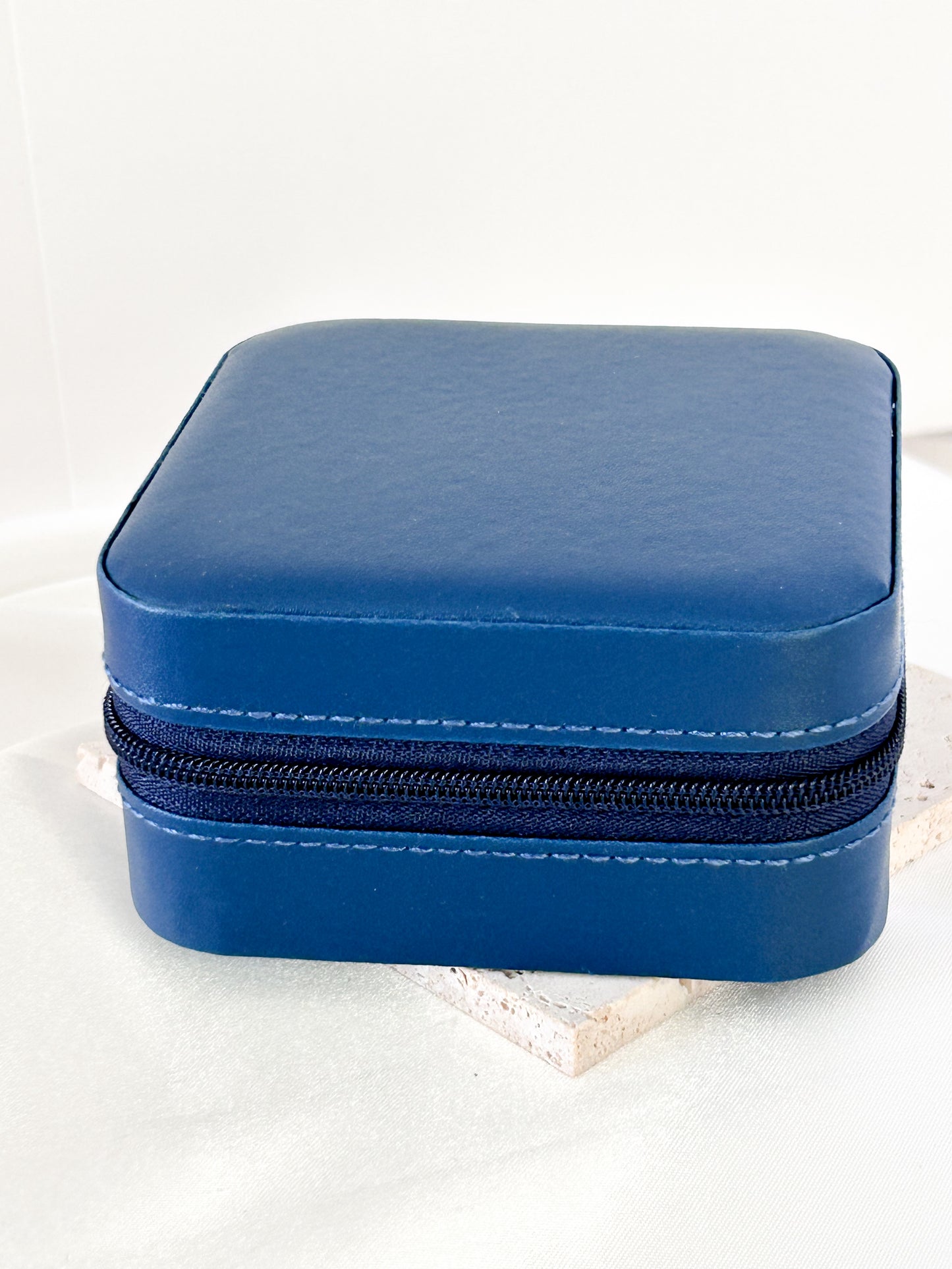 Blue jewelry case with a zipper on a white background