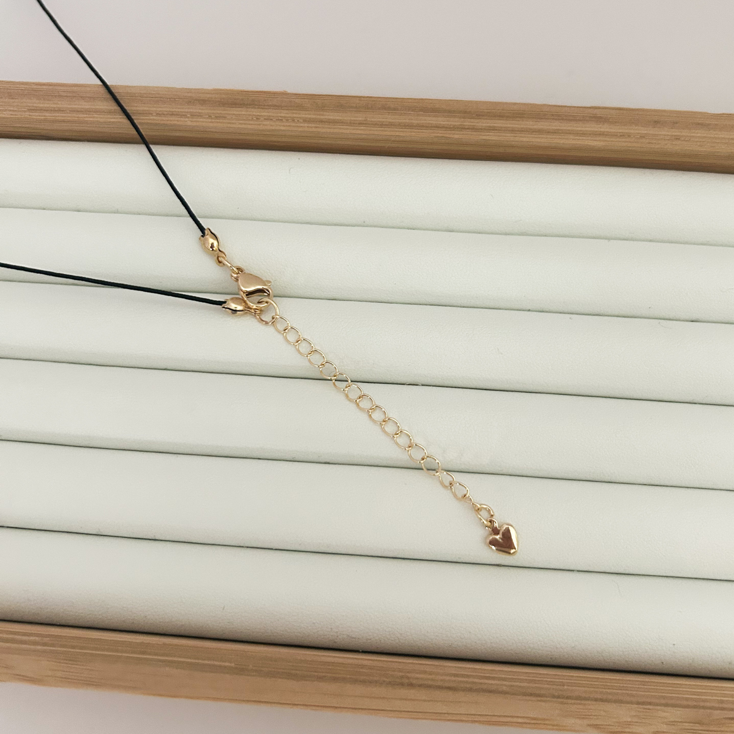 Gold chain necklace with heart pendants on a white and wooden background
