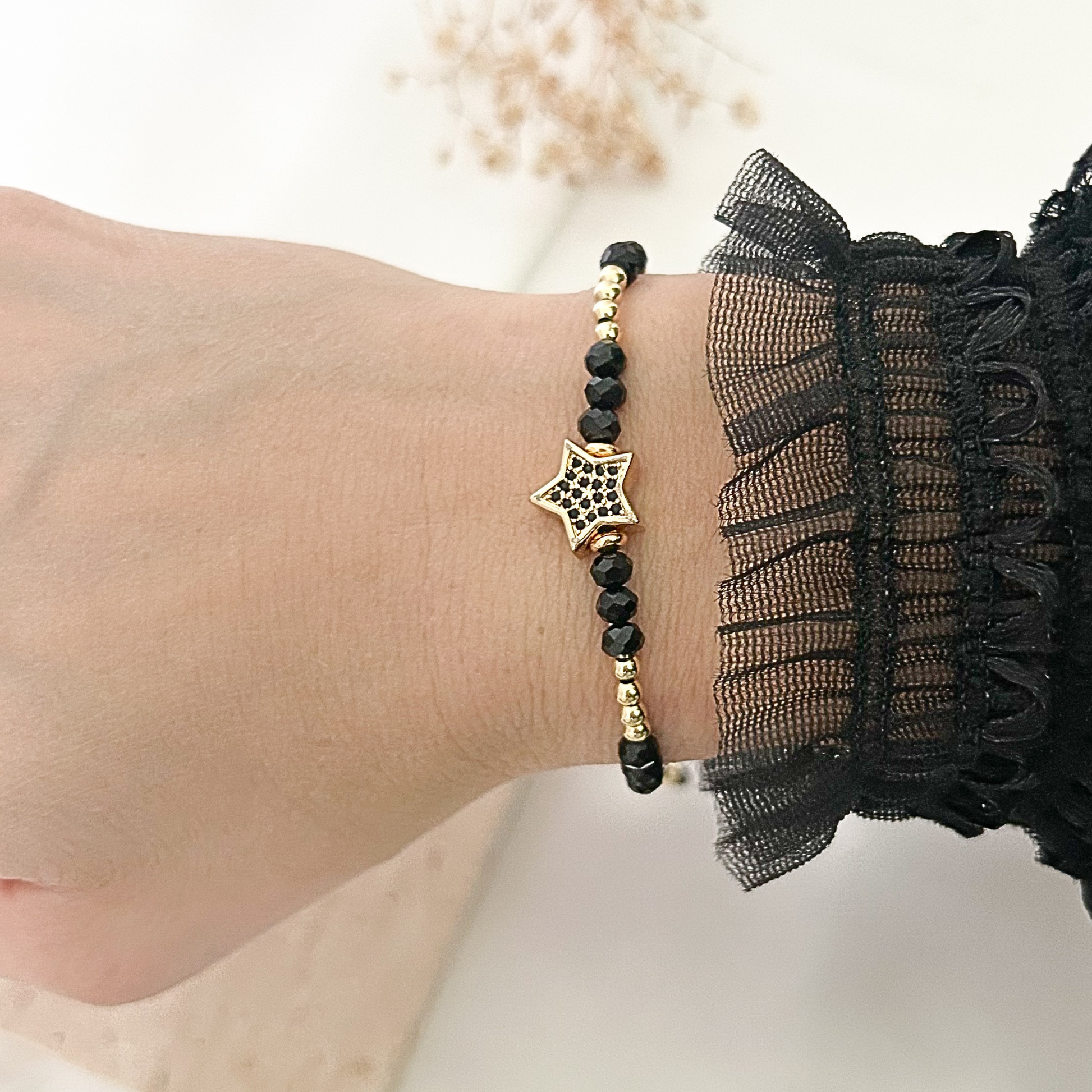 Delicate black beaded bracelet worn on the wrist, featuring faceted black crystals, gold-tone accents, and a star charm with black crystal details for a modern celestial-inspired look.