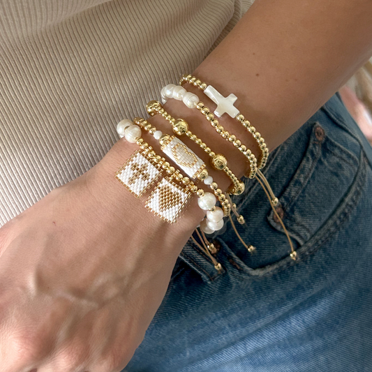 Handwoven miyuki pearl cross bracelet set with gold beads worn on wrist