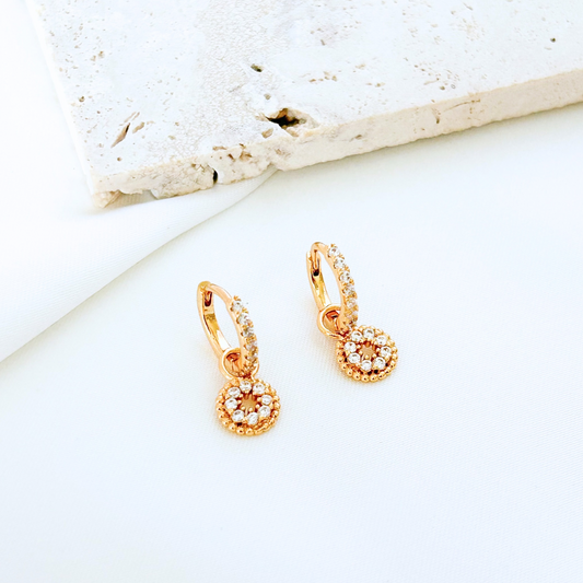 Gold earrings with gemstones on a light background
