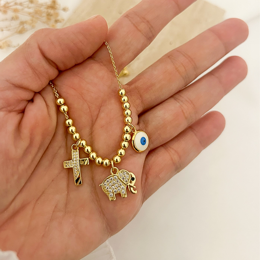 Lucky elephant necklace held in hand with cross and evil eye charms