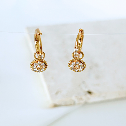Gold hoop earrings with diamond-like stones on a white background