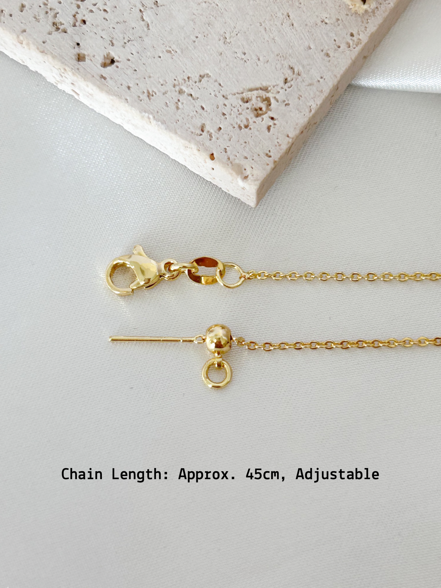 Gold necklace with clasp on a light gray surface