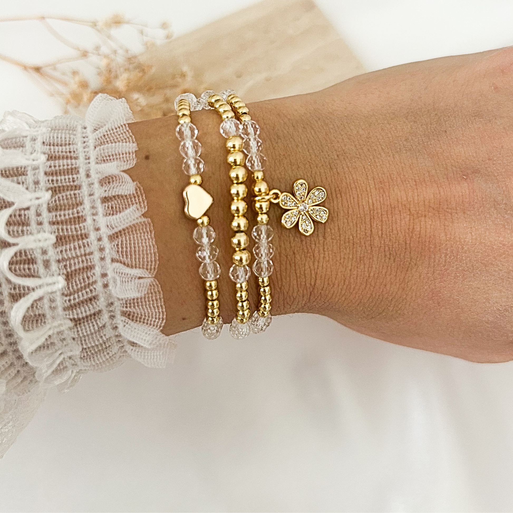 Crystal flower charm bracelet worn on wrist with heart charm