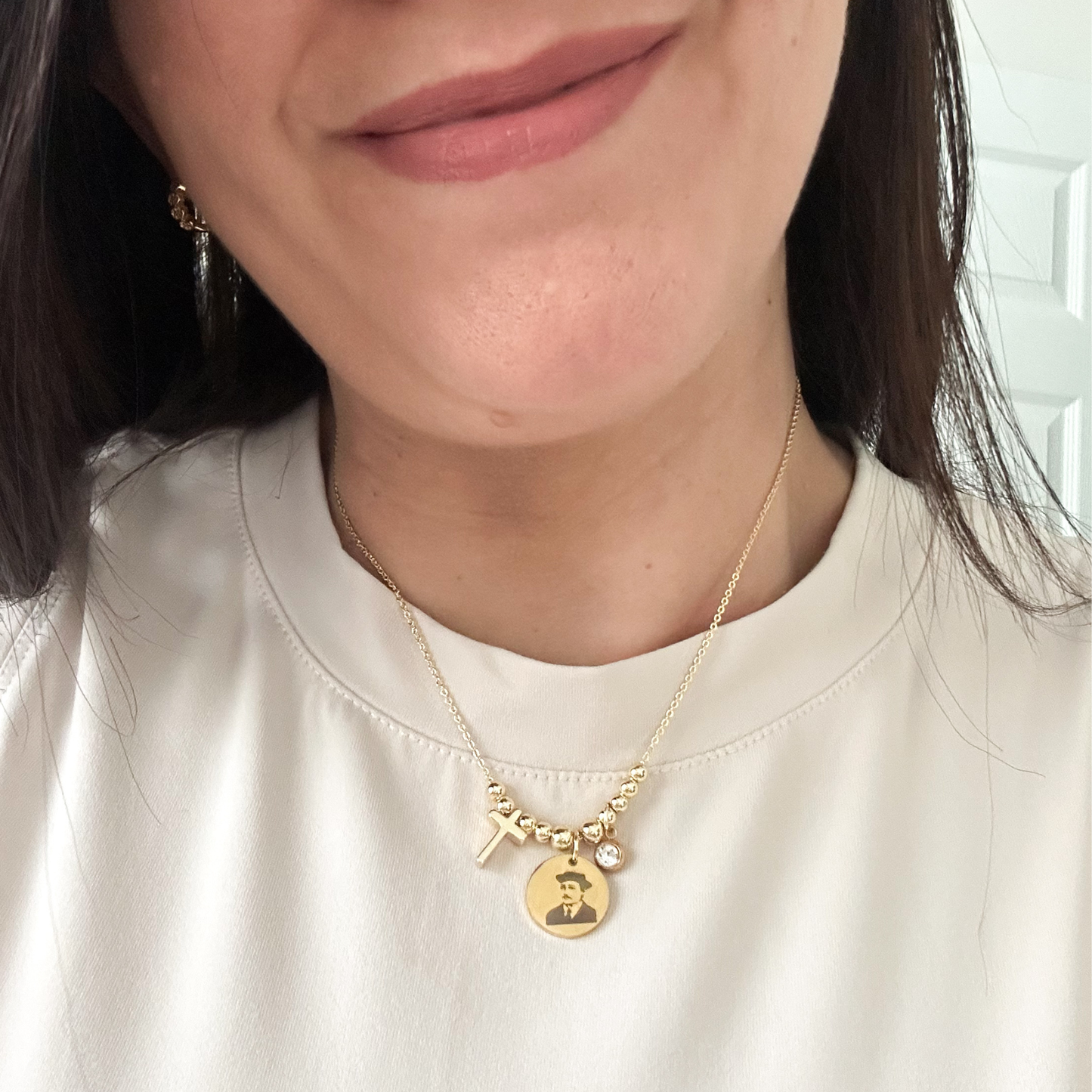 Close-up of a person wearing a gold necklace with charms on a white background