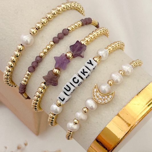 Set of beaded bracelets with gold accents on a beige surface