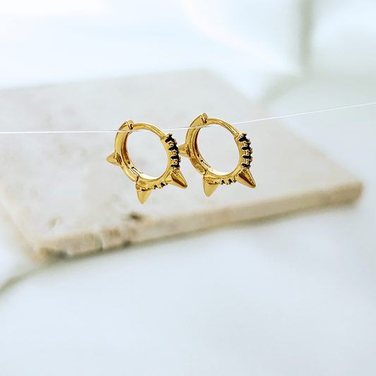 Gold hoop earrings on a marble surface with a blurred background