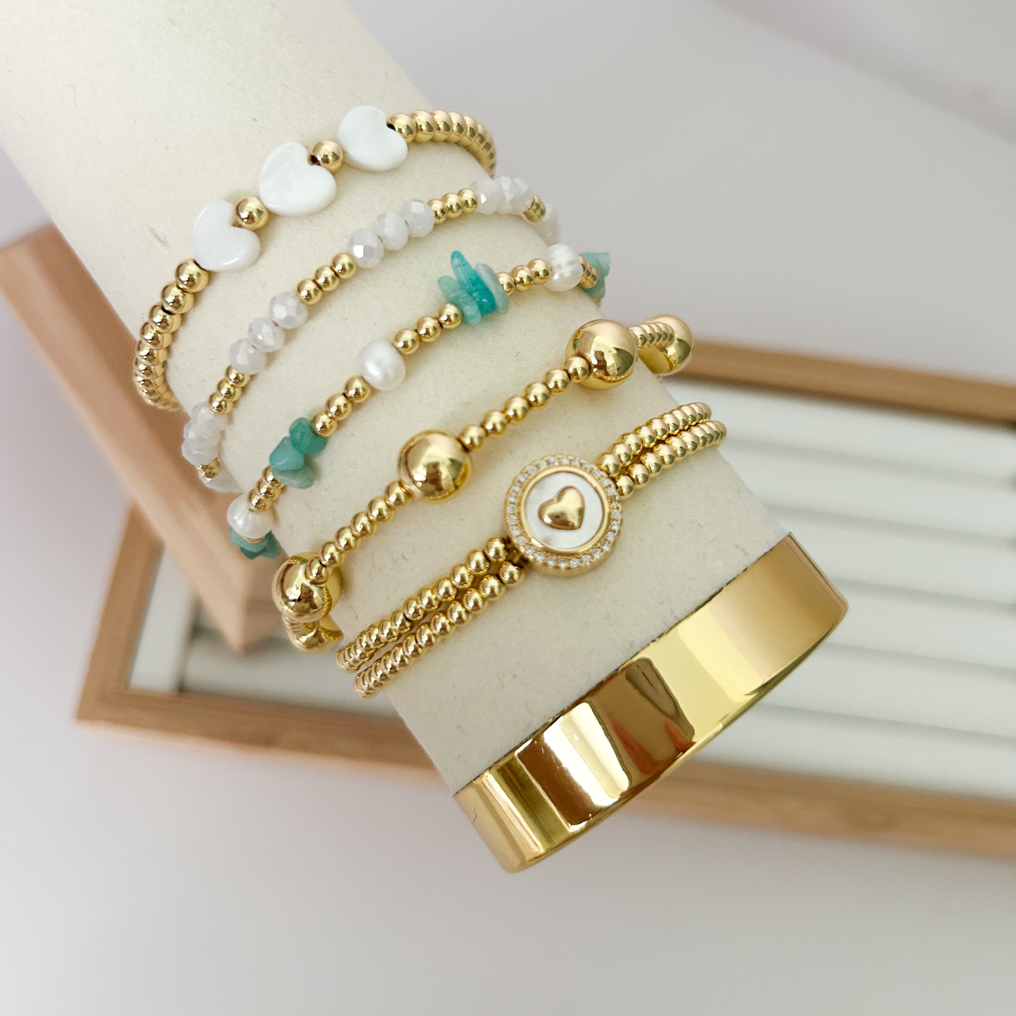 Green stone heart gold bracelet set displayed on jewelry stand