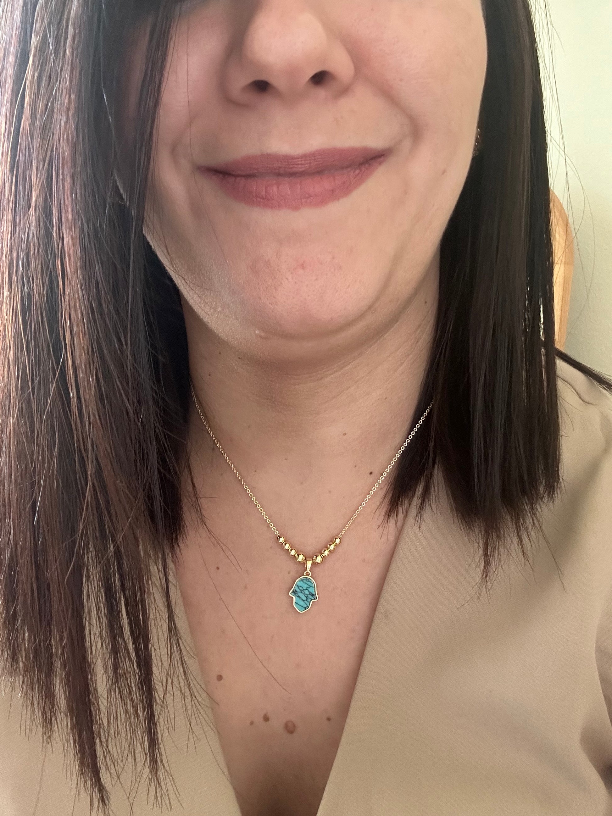 Close-up of a person wearing a gold necklace with a blue pendant.