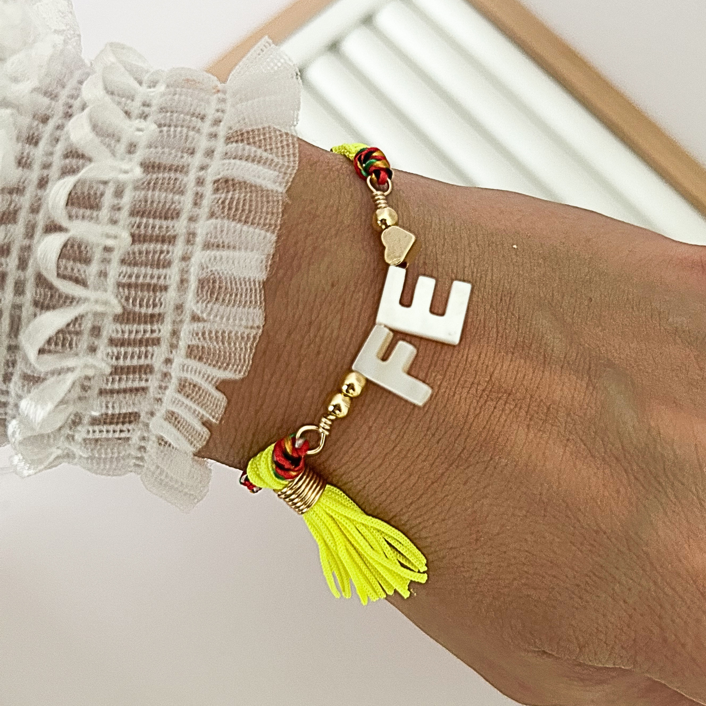 Adjustable multicolor cord faith bracelet with neon yellow tassel and white Fe letter gold charm on jewelry on the wrist