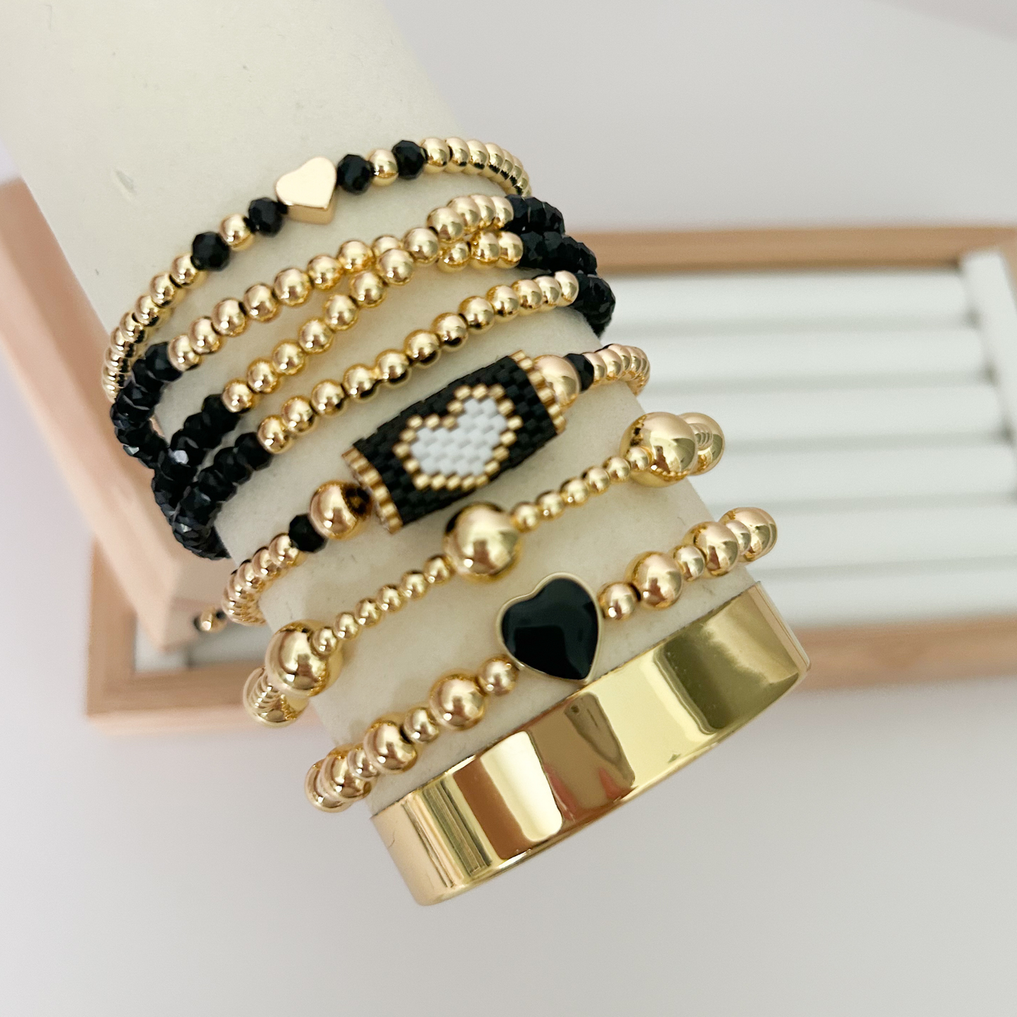 Black gold minimal heart bracelet set displayed on jewelry stand