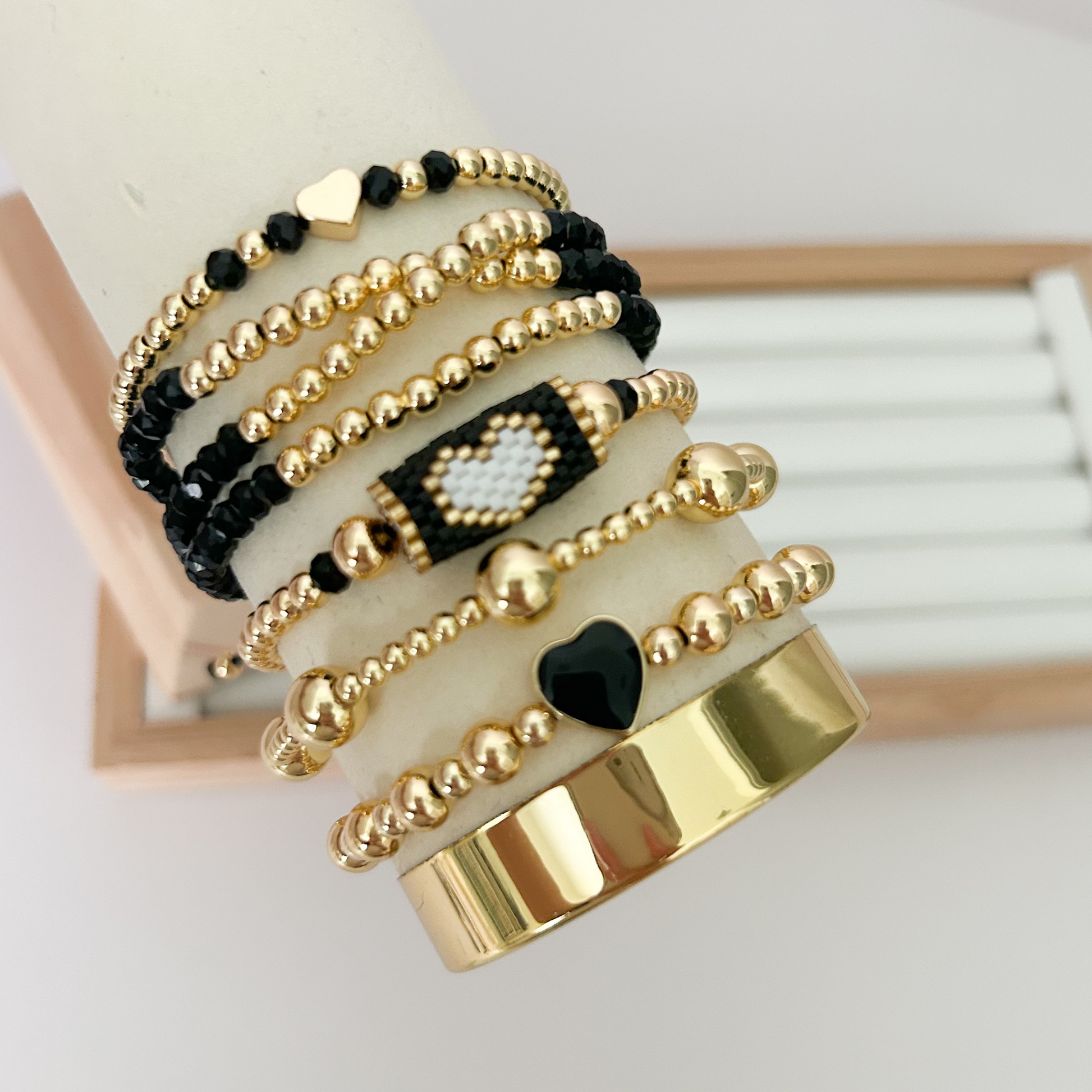 Black gold minimal heart bracelet set displayed on jewelry stand