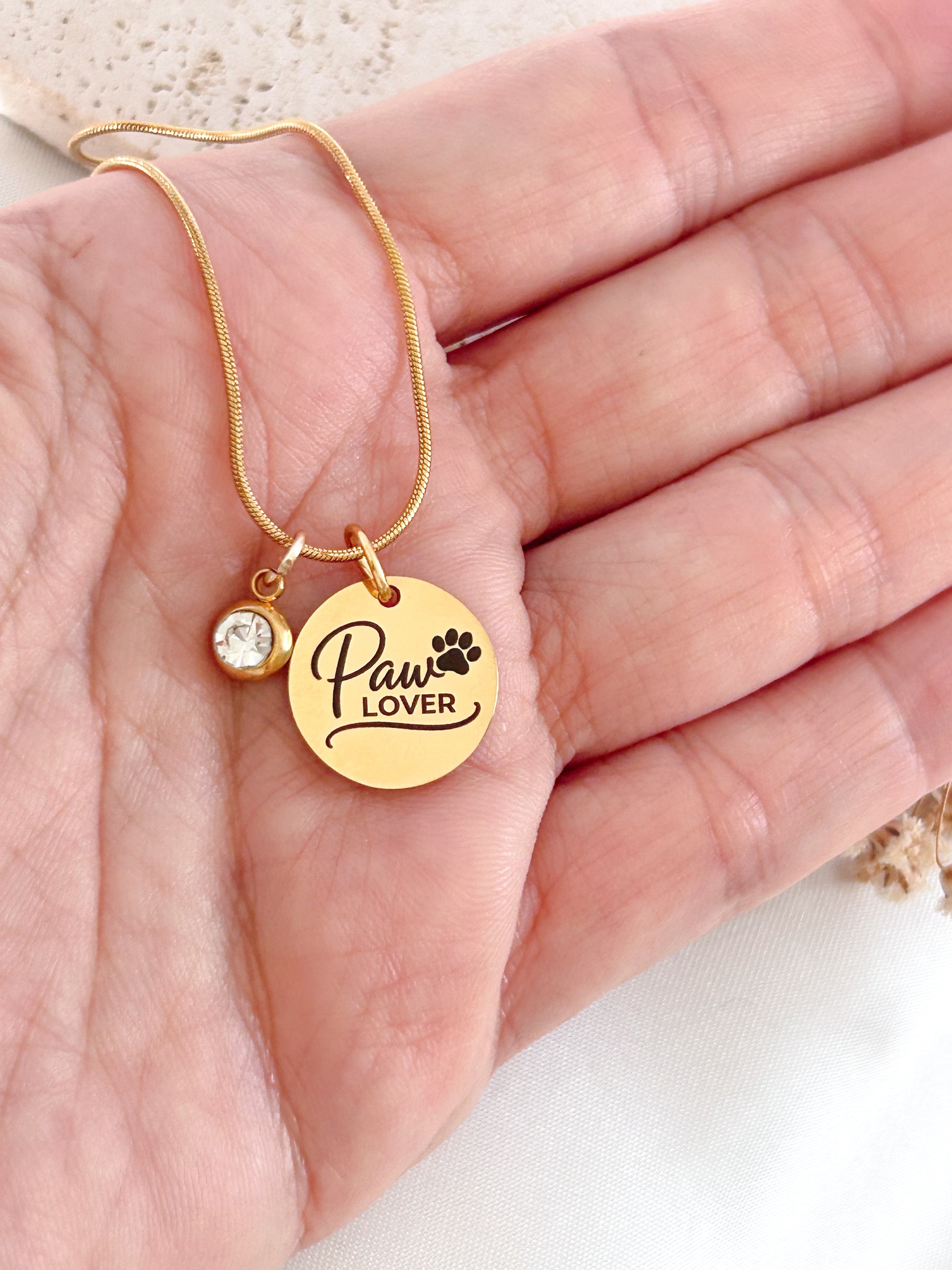 Gold necklace with 'Paw Lover' pendant on a hand