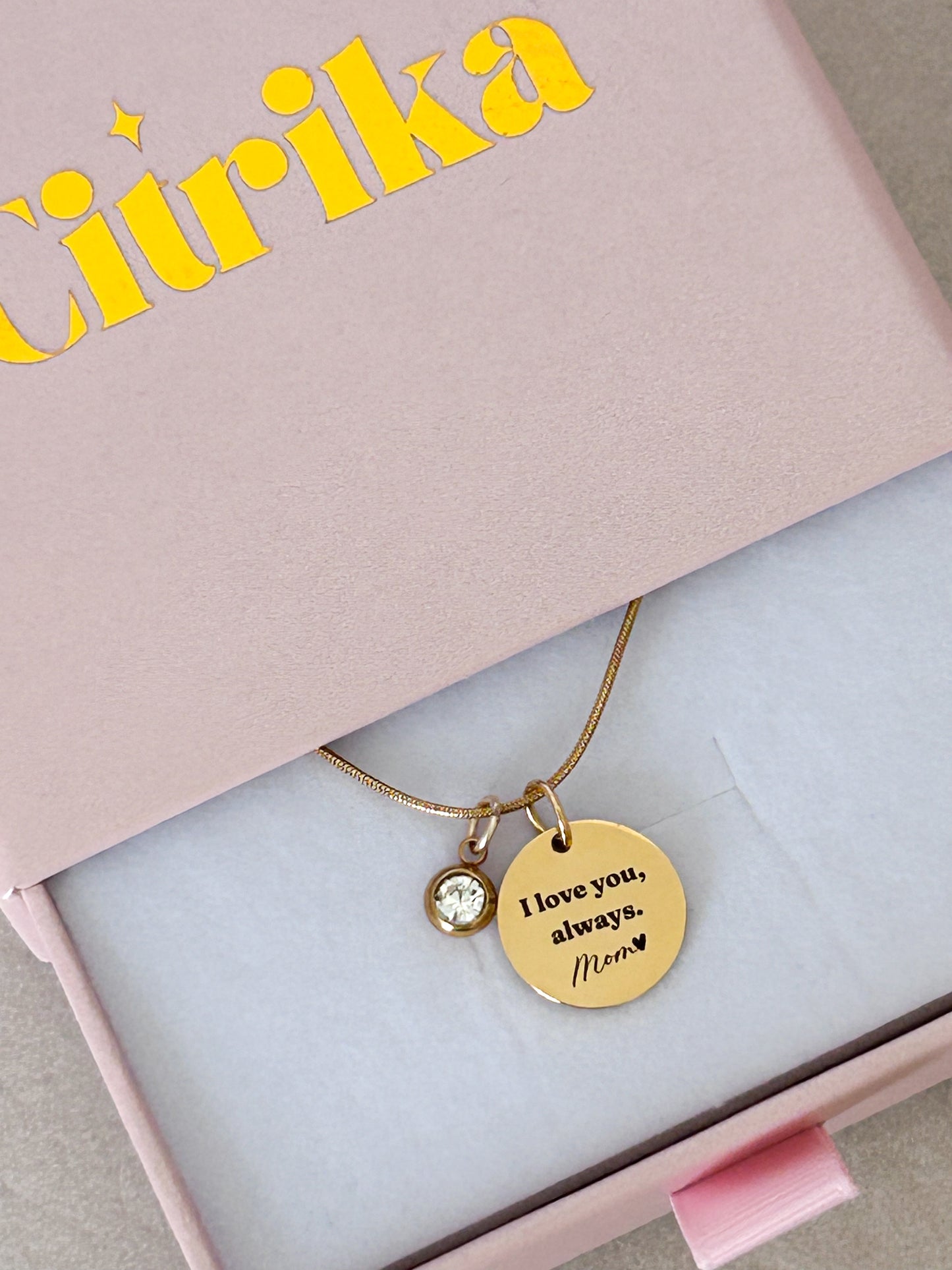 Gold necklace with a round pendant in a pink box with 'Céréka' branding.