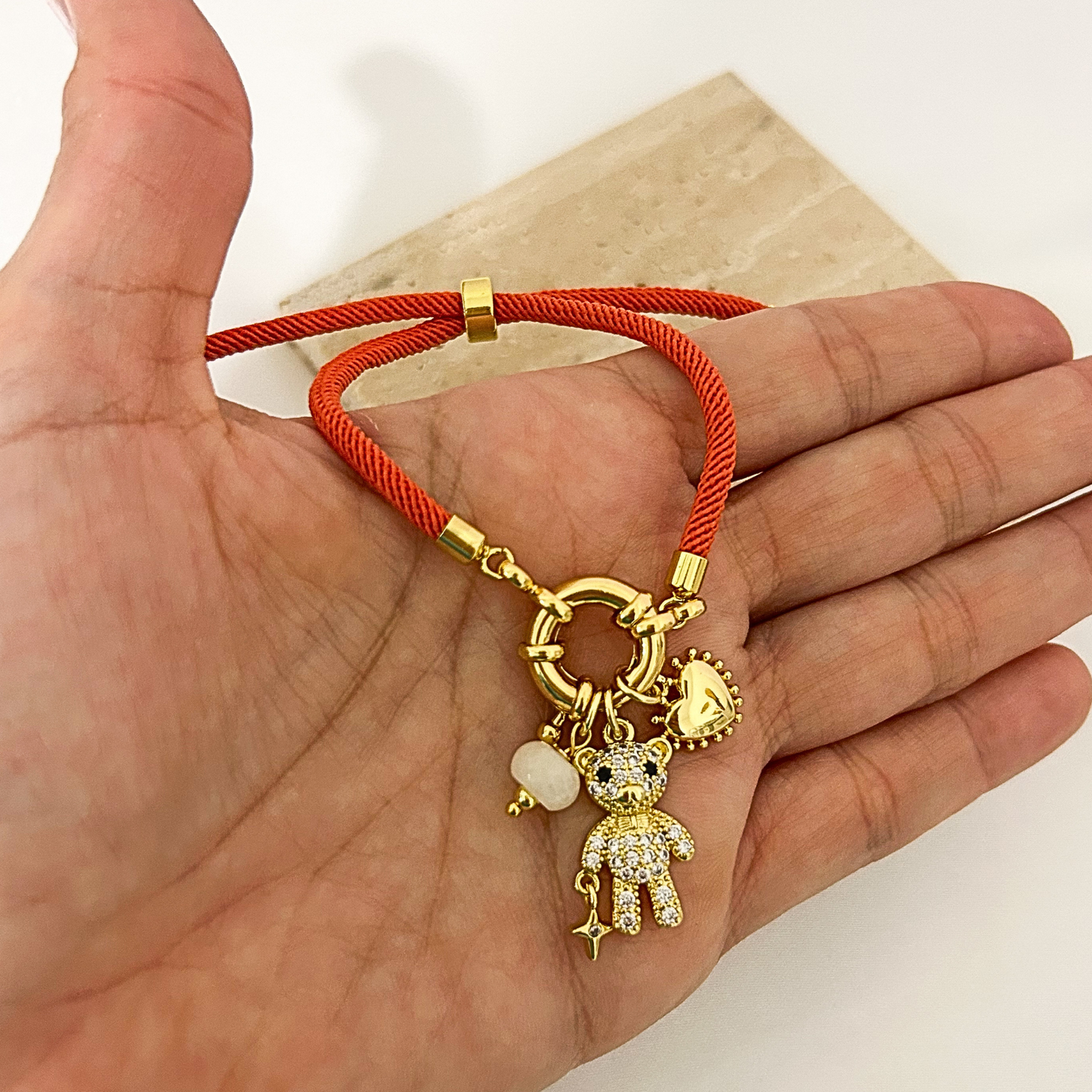 Orange cord bracelet with teddy bear charm and heart charm