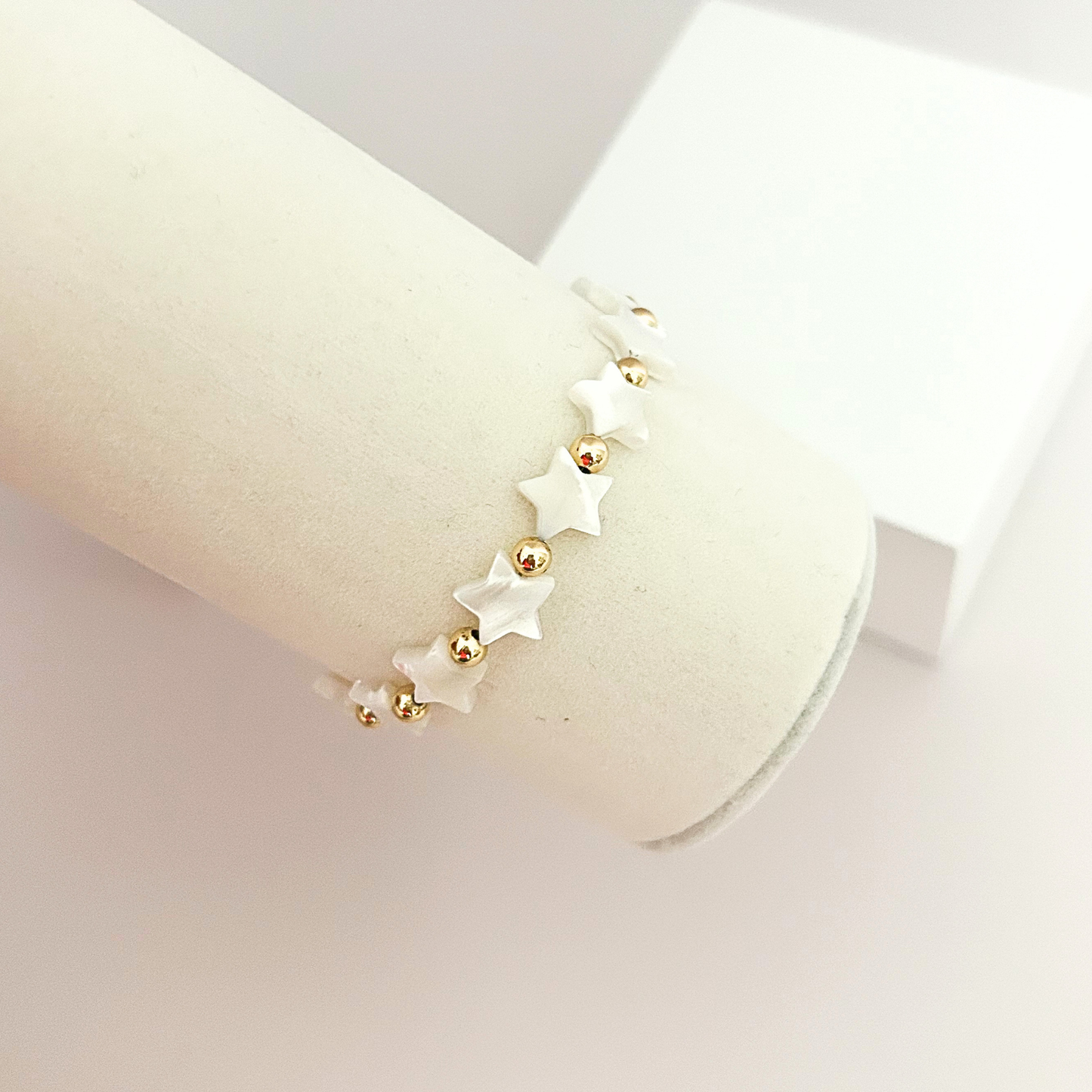 Elegant handcrafted bracelet with luminous white stars, polished gold beads, and an adjustable cord for a comfortable fit.