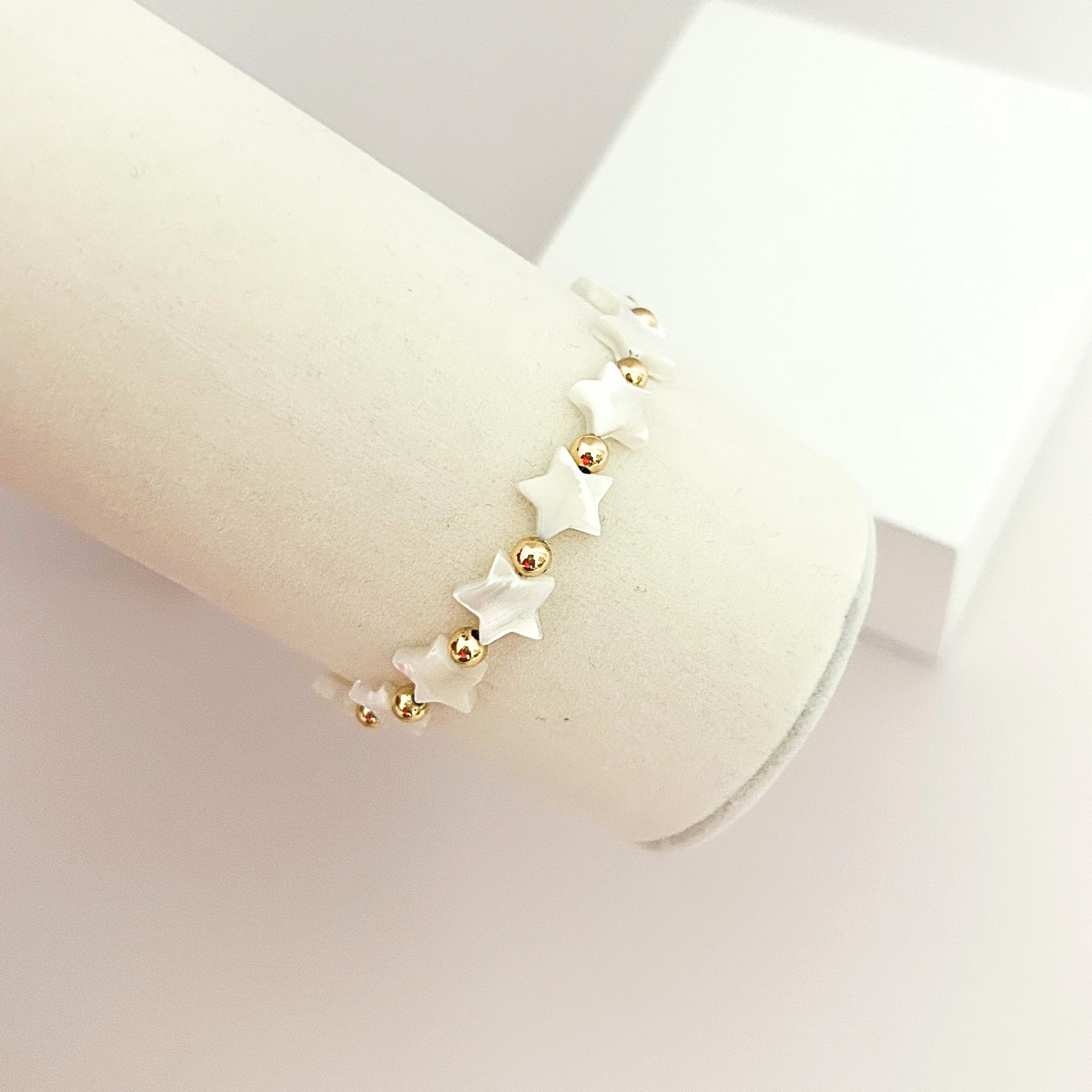 Elegant handcrafted bracelet with luminous white stars, polished gold beads, and an adjustable cord for a comfortable fit.