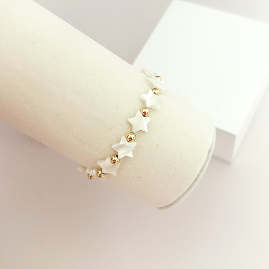 Elegant handcrafted bracelet with luminous white stars, polished gold beads, and an adjustable cord for a comfortable fit.