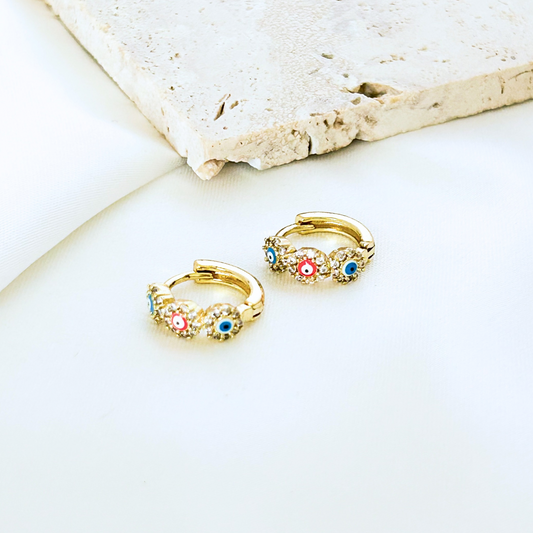 Gold hoop earrings with colorful gemstones on a light background