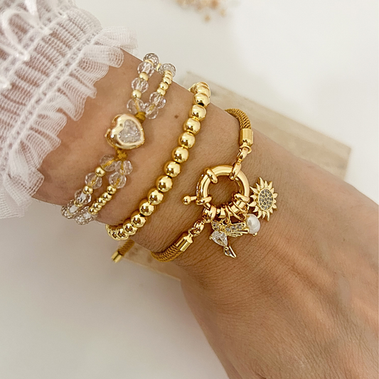 Stacked gold bracelet set with crystal heart, gold bead, and sun hummingbird charm bracelets