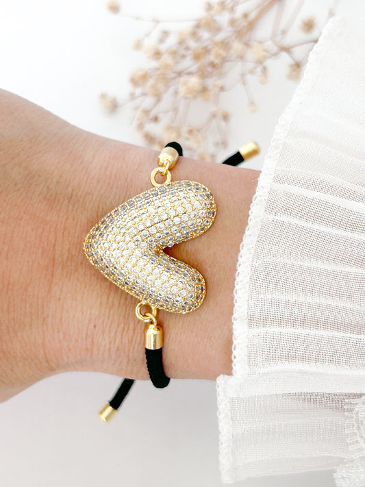 Bangle with heart-shaped design on a wrist against a white background
