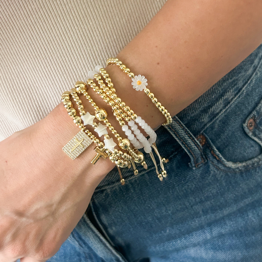 Daisy cross bracelet set with white crystal beads and gold charms worn on wrist