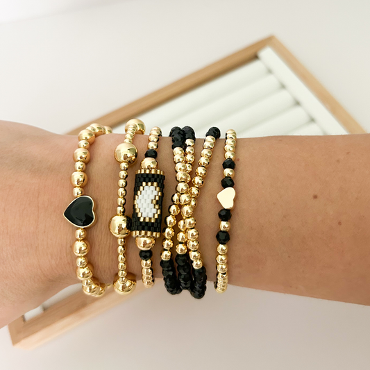 Black crystal and gold bracelet stack with small heart charm styled on wrist