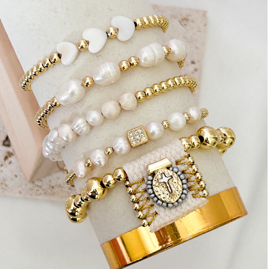 Set of gold and pearl bracelets on a marble surface