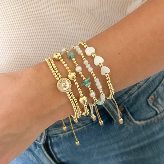Green stone heart bracelet set with pavé medallion and gold beads worn on wrist