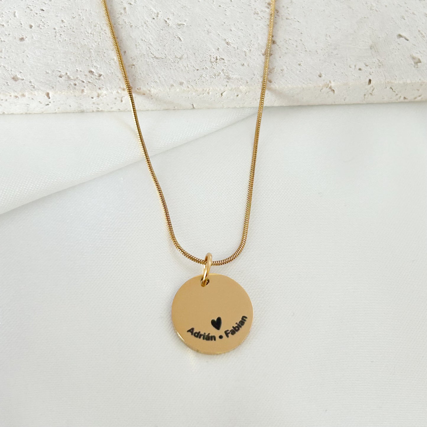 Gold necklace with a round pendant on a light background