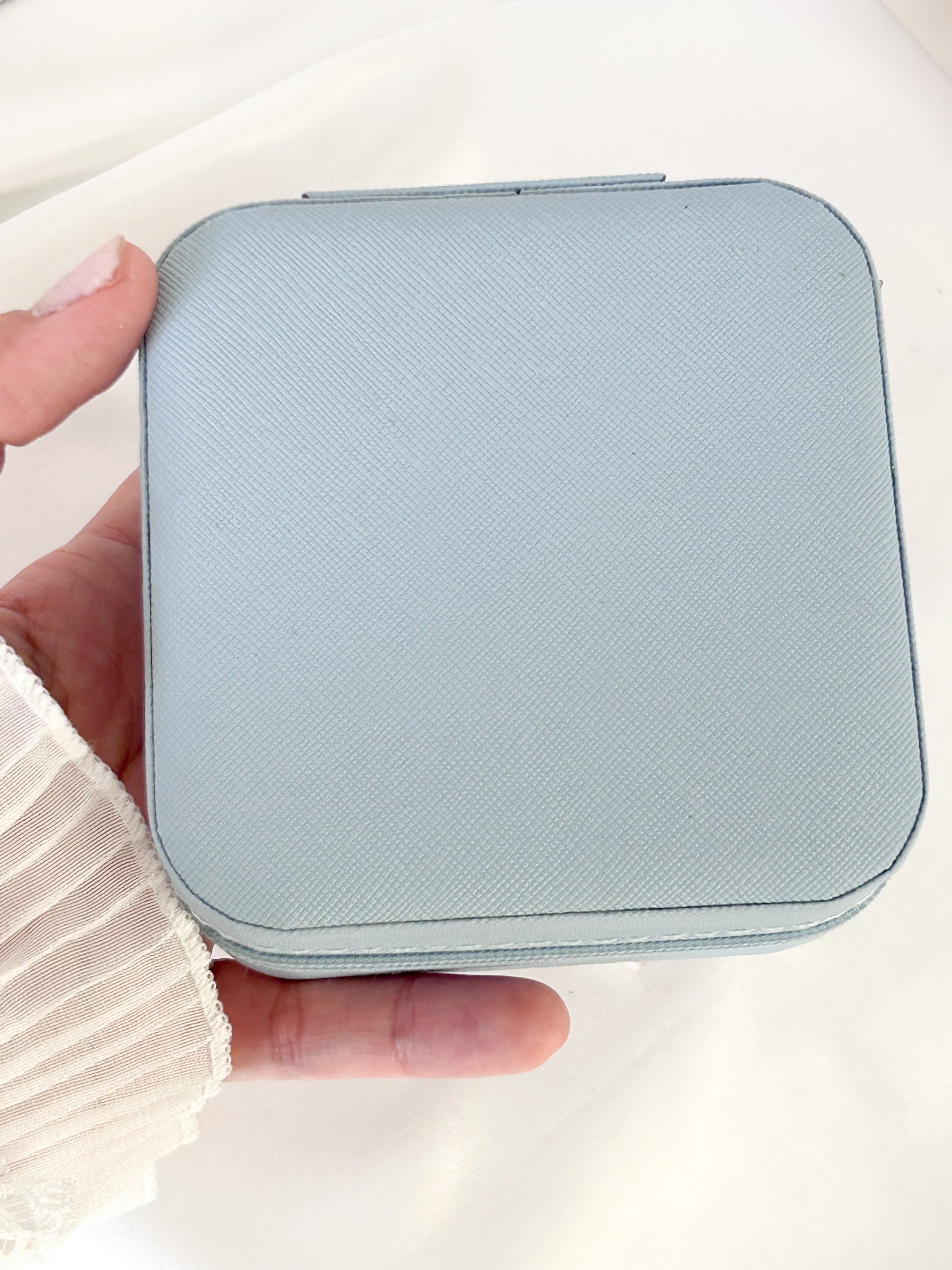 Light blue wallet held in a hand against a white background