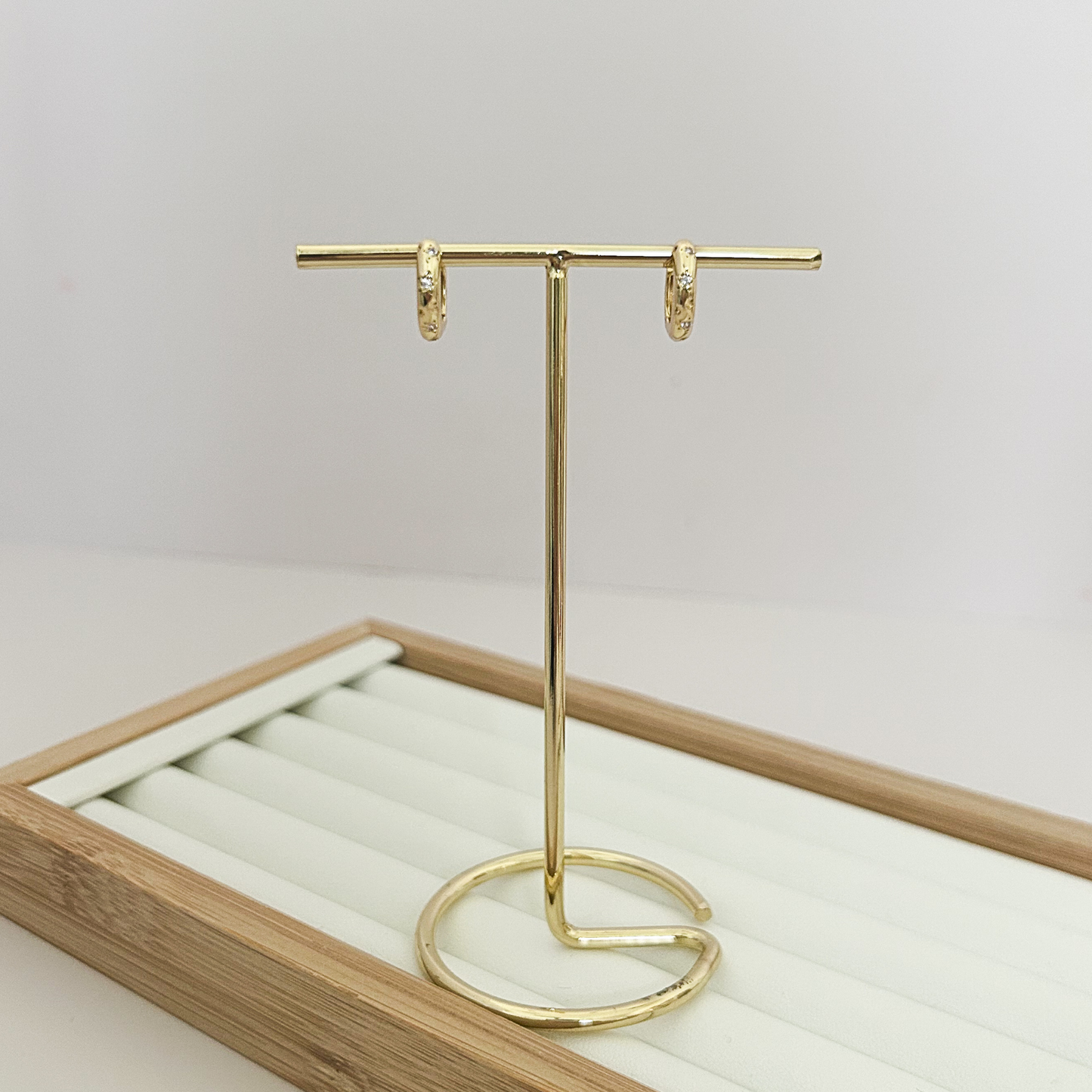 Small gold huggie hoop earring held between fingers