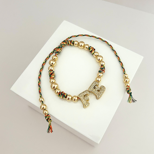 Adjustable gold-tone bracelet featuring sparkling “FE” letters and colorful braided cord accents, inspired by faith and everyday elegance.