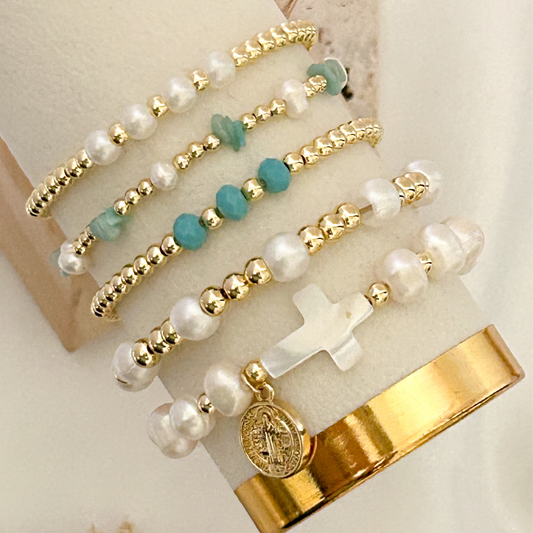 Bracelets with pearls, turquoise beads, and gold accents on a white surface