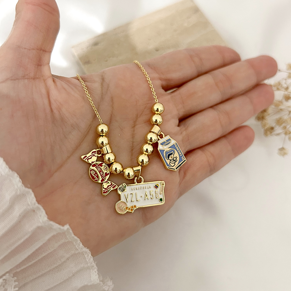Hand holding Venezuela nostalgia charm necklace to show detail