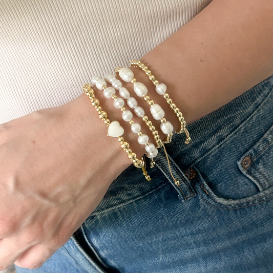 White heart pearl bracelet set with gold beads worn on wrist