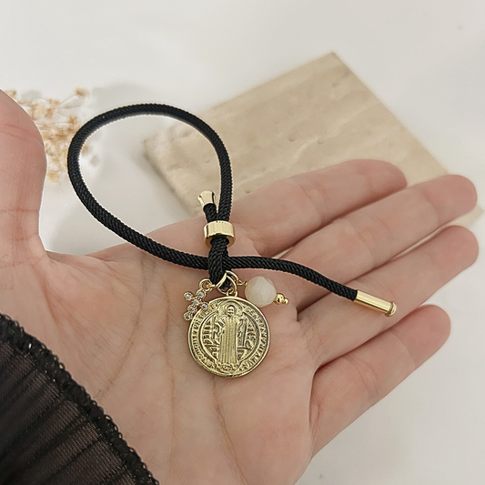 Hand holding black Saint Benedict charm bracelet to show size