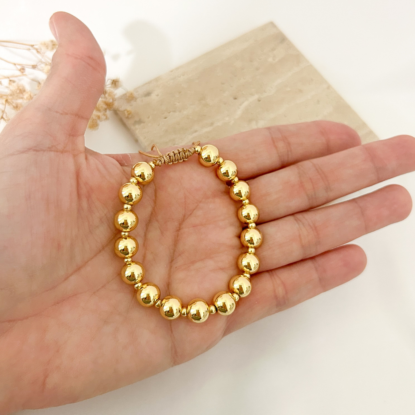 Gold bead bracelet held in hand
