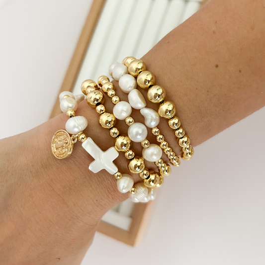 Gold faith bracelet stack with baroque pearls and Saint Benedict medallion styled on wrist