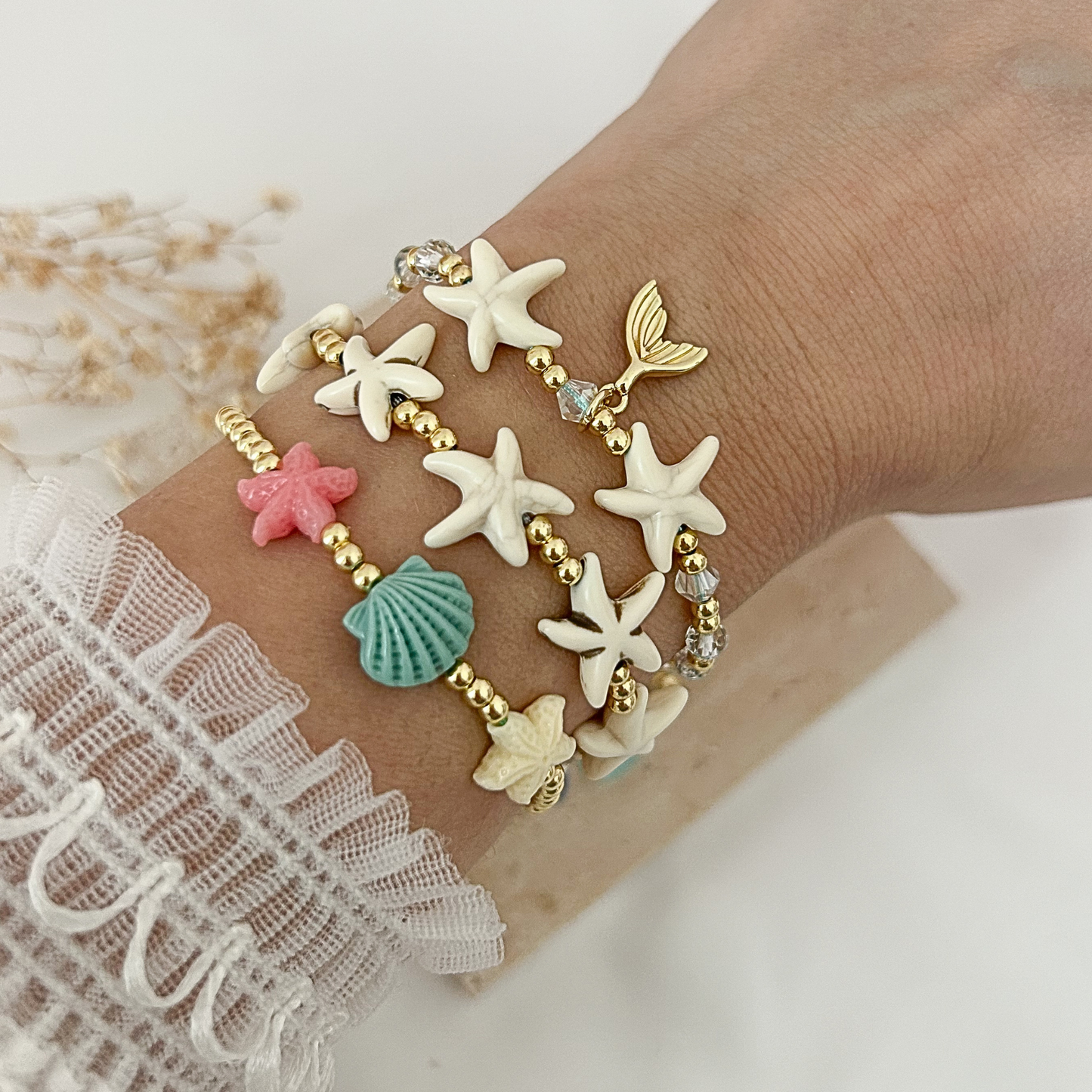 Beach-inspired bracelet stack featuring starfish, seashell, crystal beads, and mermaid tail charms with gold accents. A colorful summer jewelry set perfect for layering or wearing individually.