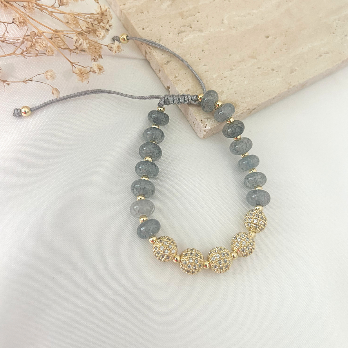 Gray crystal beaded bracelet with pavé gold accent beads held in hand