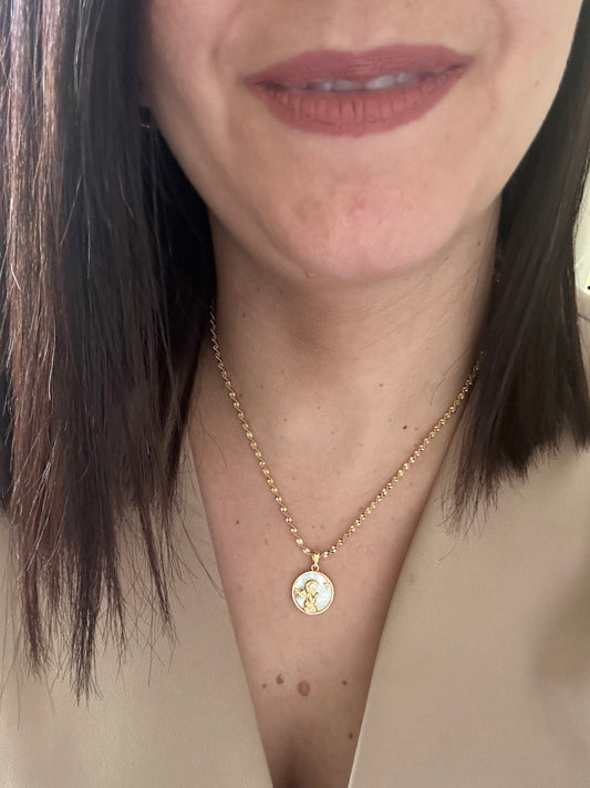 Close-up of a person wearing a gold necklace with a pendant.