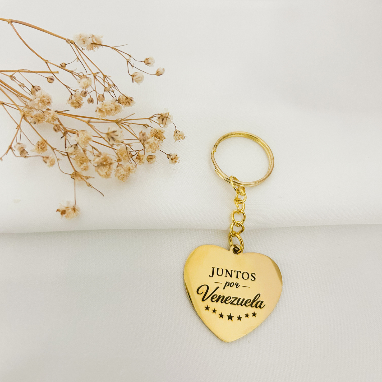 Gold stainless steel heart keychain engraved with “Juntos por Venezuela”, created to support humanitarian aid in Venezuela.